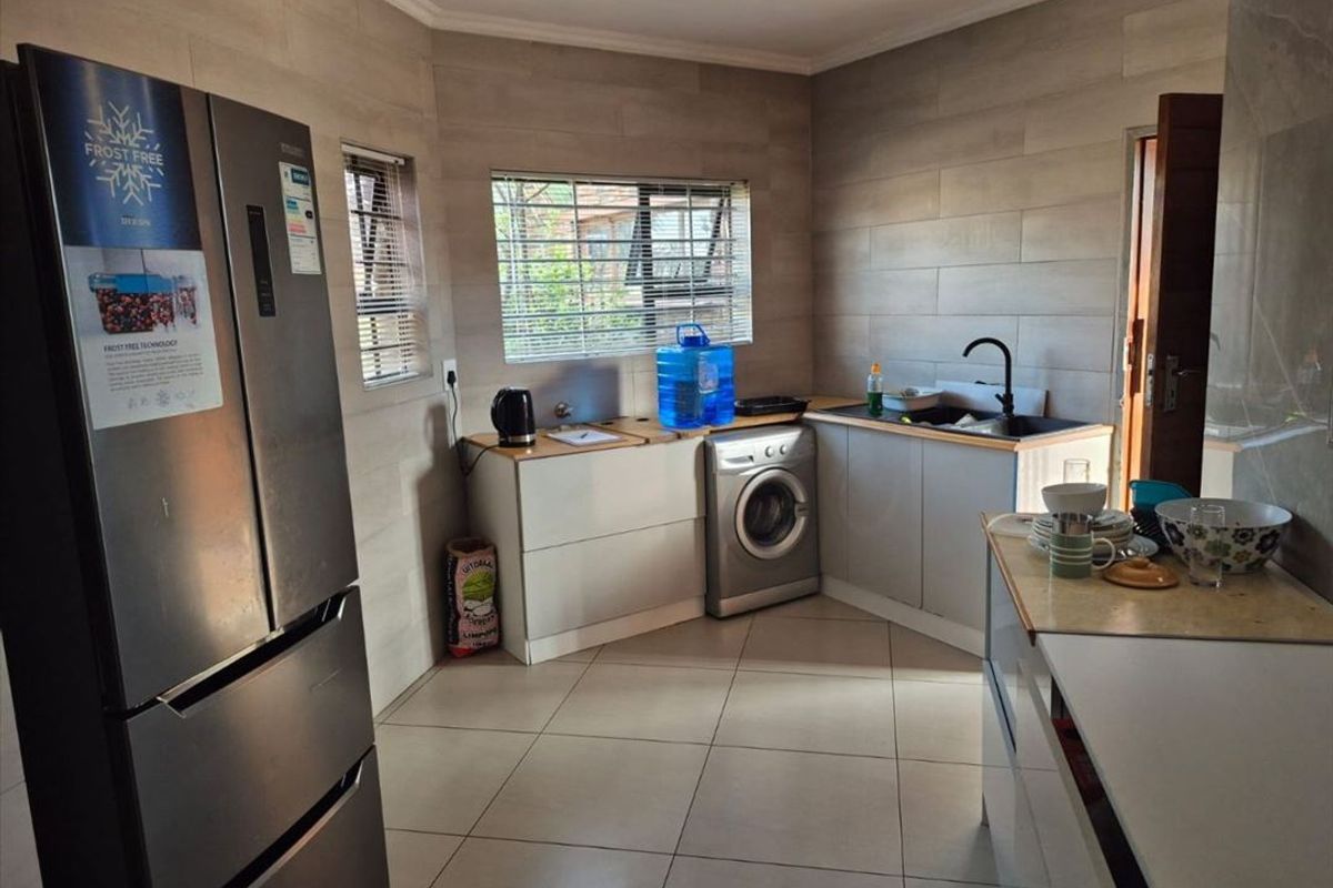 A functional kitchen featuring modern tiled wall finishes, built-in cabinetry, and a dedicated space for laundry appliances.