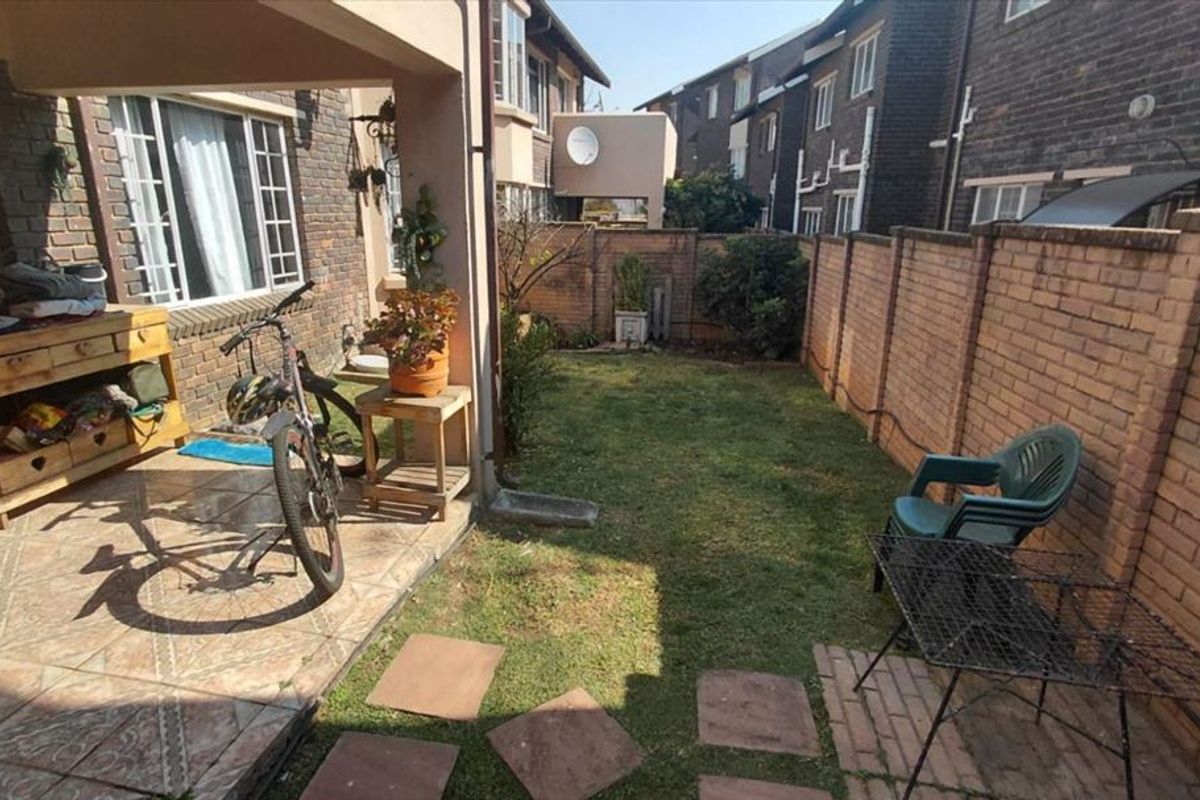 A private rear garden featuring a tiled patio area and a brick-walled perimeter, offering a compact outdoor space for relaxation.