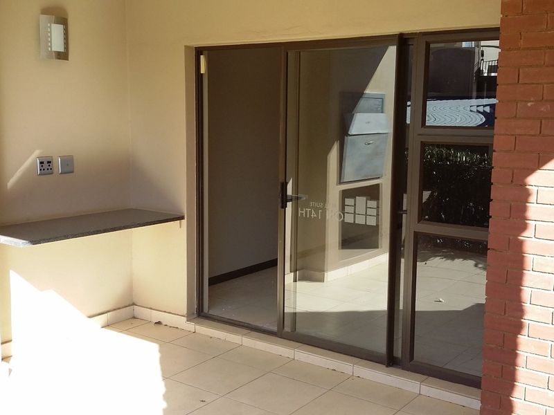 A covered patio area featuring tiled flooring, a built-in stone shelf, and sliding glass doors providing access to the interior.