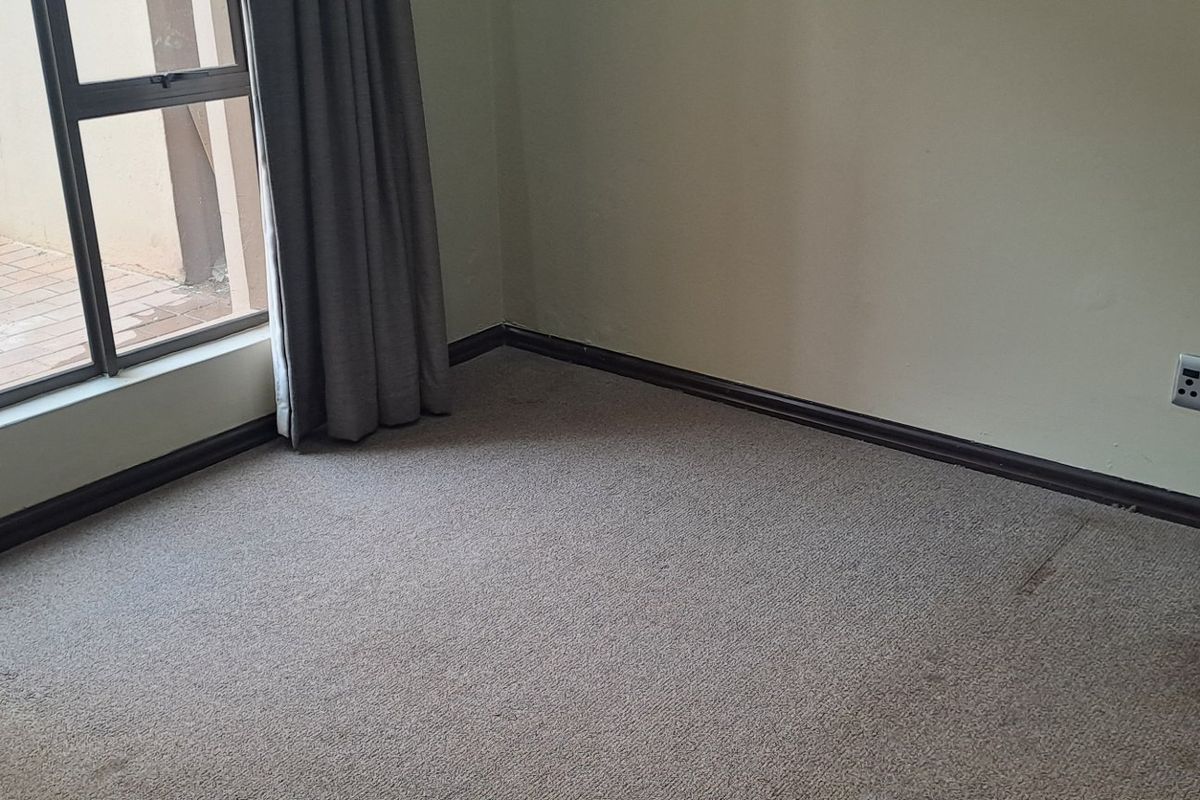 An empty bedroom featuring carpet flooring, a sliding glass door providing access to an outdoor area, and neutral wall finishes.