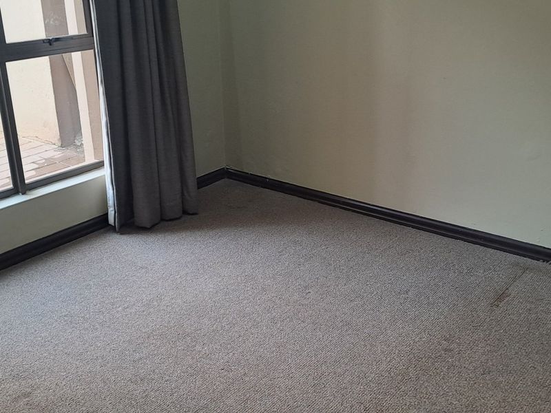 An empty bedroom featuring carpet flooring, a sliding glass door providing access to an outdoor area, and neutral wall finishes.