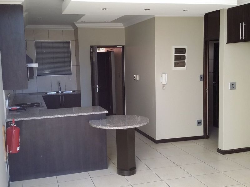 Open-plan kitchen and living area featuring granite countertops, dark wood cabinetry, tiled flooring, and recessed lighting in a neutral, well-maintained space.