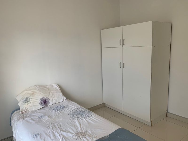 A simple bedroom featuring tiled flooring and a white built-in wardrobe, offering a clean and functional space.