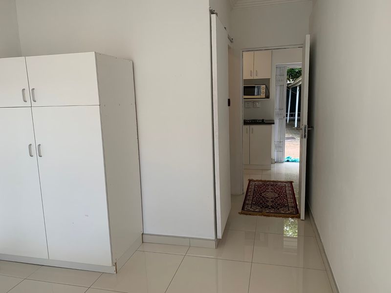 A bright hallway with tiled flooring and a built-in cupboard, providing access to the kitchen area.