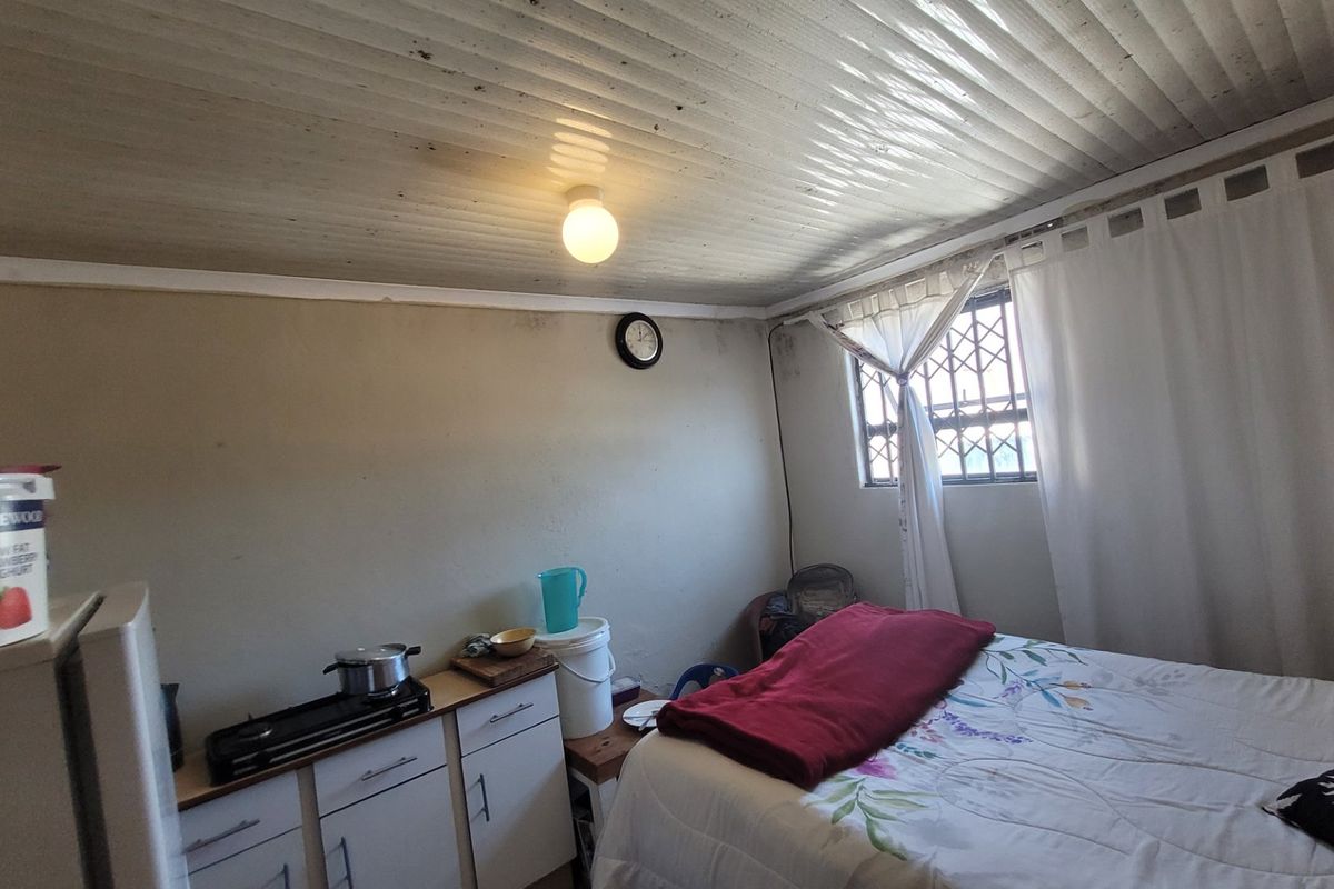 A bedroom featuring a security gate on the window and built-in cabinetry, showing signs of wear and requiring maintenance on the ceiling and walls.