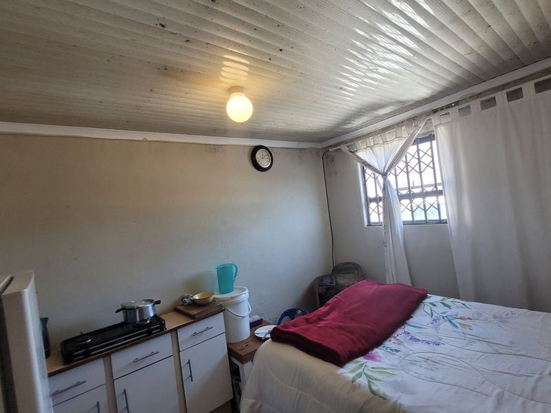 A bedroom featuring a security gate on the window and built-in cabinetry, showing signs of wear and requiring maintenance on the ceiling and walls.