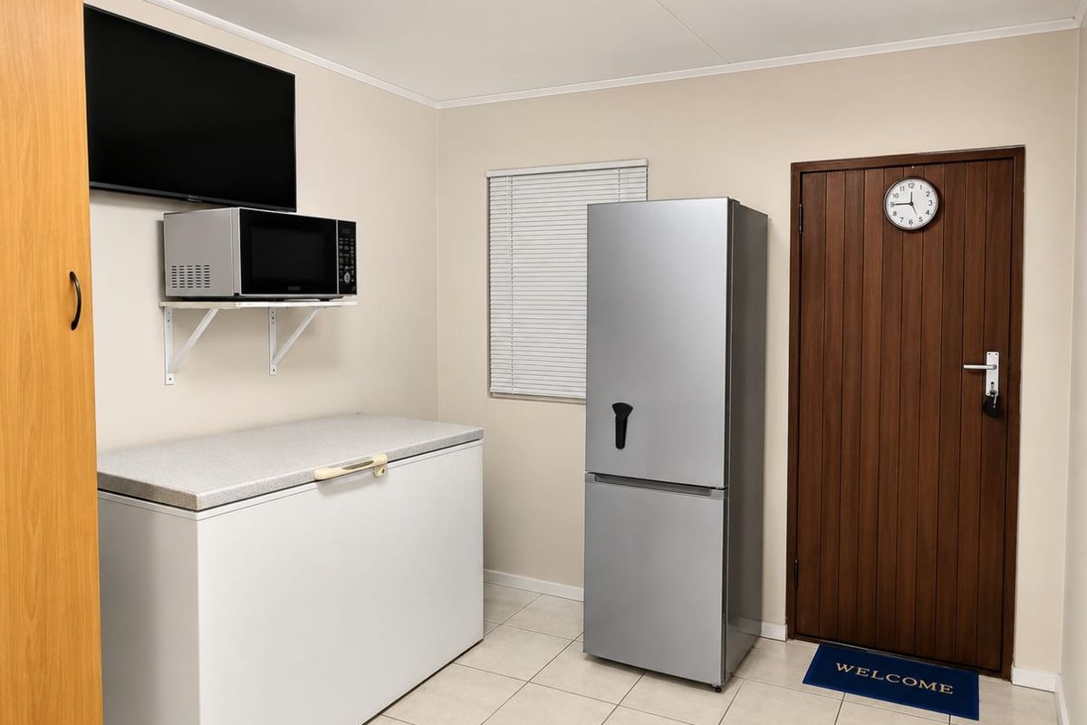 A clean and functional utility space featuring tiled flooring, a solid core door, and venetian blinds, suitable for storage or laundry purposes.