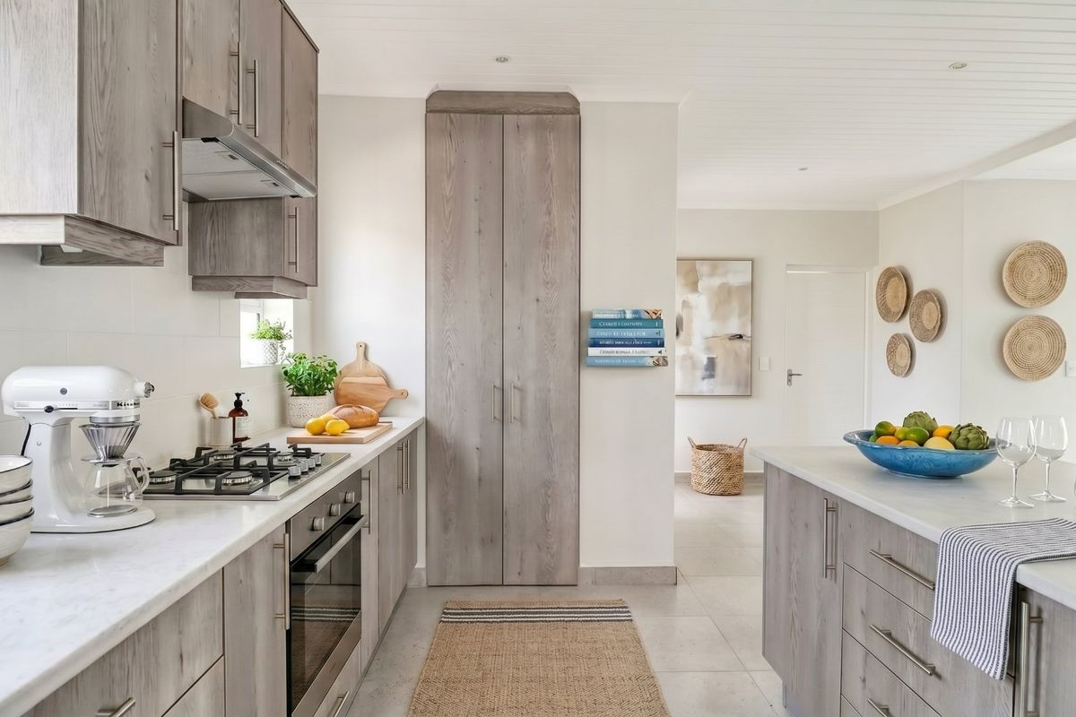 Modern kitchen featuring light wood-grain cabinetry, stone countertops, integrated gas cooktop, built-in oven, and a central island, finished with neutral tiled flooring.