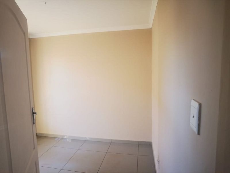 An empty bedroom featuring neutral wall paint, tiled flooring, and a coved ceiling, providing a blank canvas for personalization.
