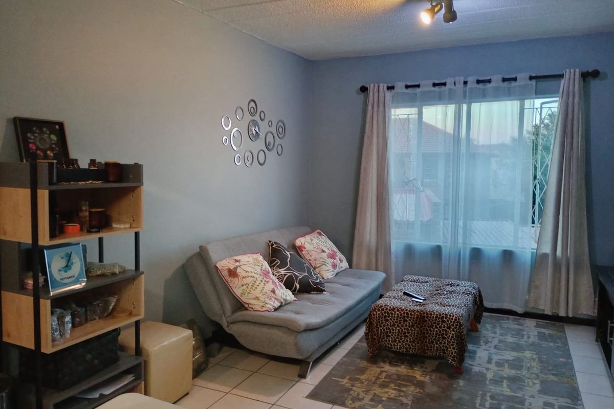 A living room featuring tiled flooring, a large window with security bars, and a ceiling-mounted spotlight fixture.