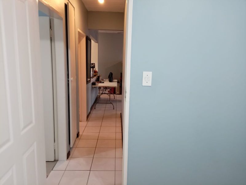 A view through a hallway with tiled flooring, connecting to other rooms in the apartment.