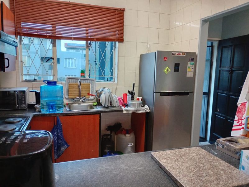 A functional kitchen featuring built-in cabinetry, a stainless steel sink, and tiled backsplash, offering a practical layout for daily meal preparation.