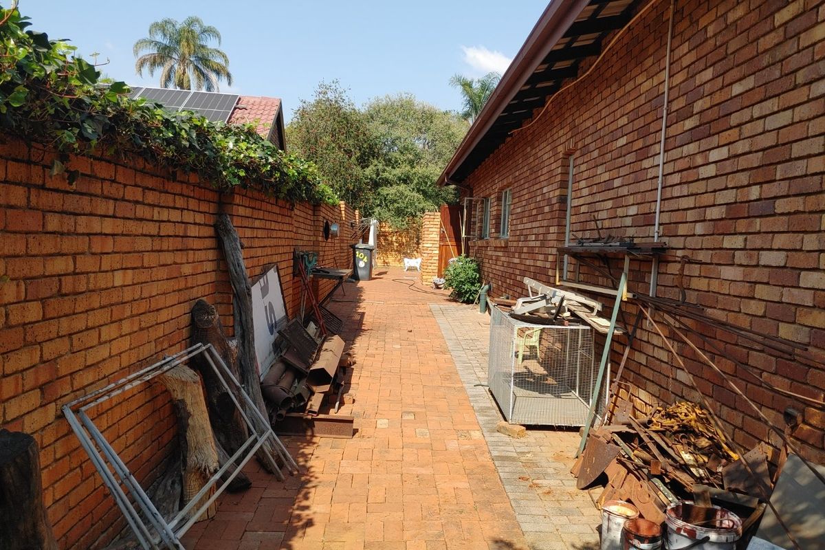 A side passage or rear exterior area featuring brick paving and a brick boundary wall.
