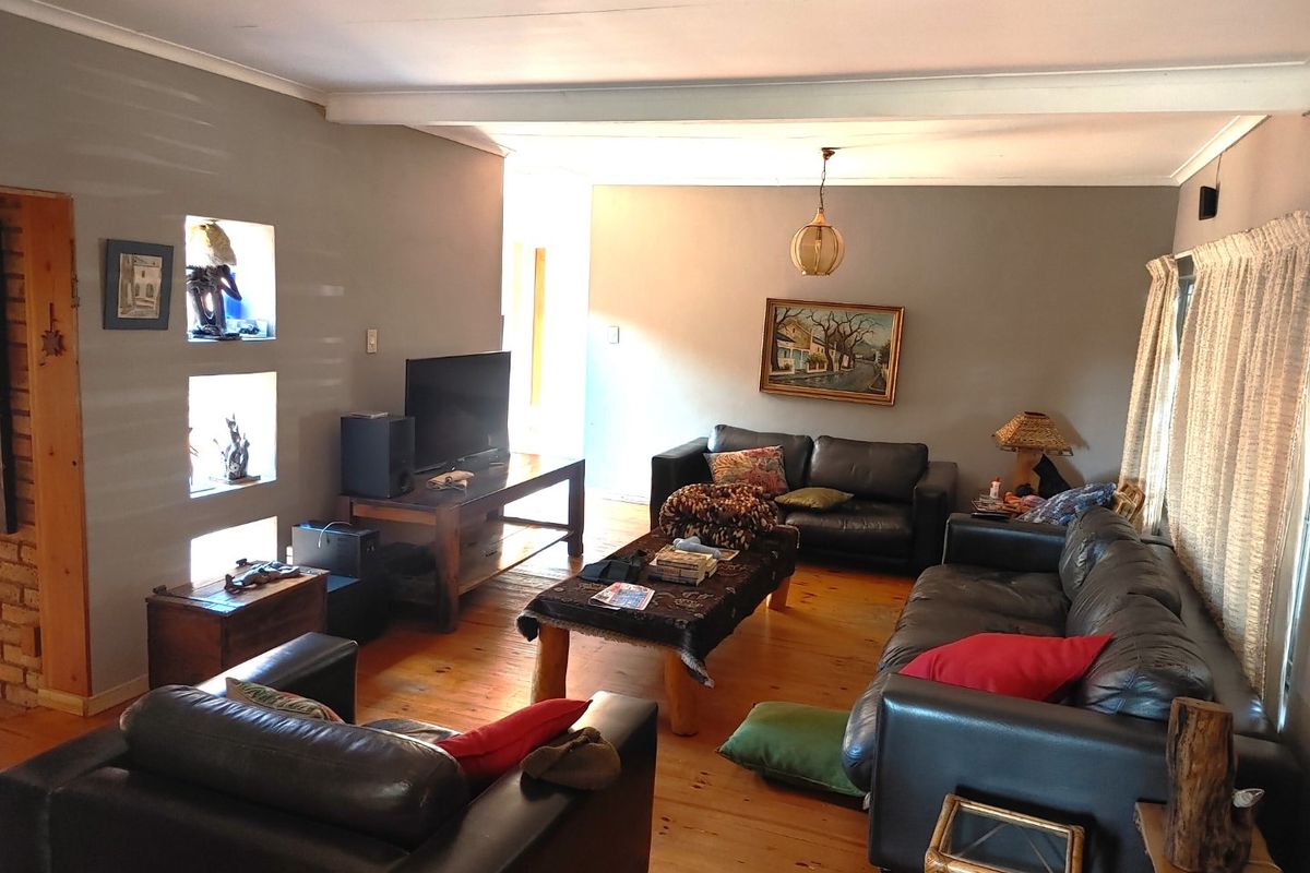 Spacious living room featuring warm timber flooring, recessed wall niches, and neutral grey walls, offering a comfortable and inviting atmosphere.