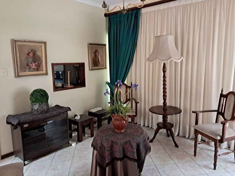 A living room area featuring tiled flooring and a serving hatch connecting to the adjacent space, finished with neutral wall tones.