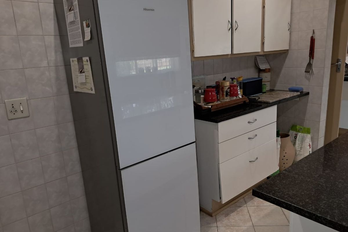 A functional kitchen area featuring tiled walls, granite countertops, and white cabinetry with visible wear and missing kickplate detailing.