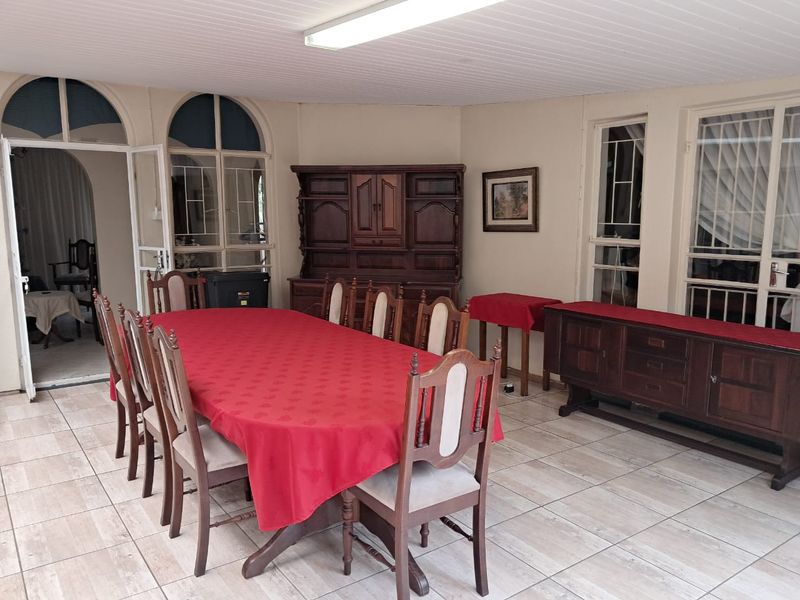 Spacious dining room featuring tiled flooring, timber-framed windows, and a classic tongue and groove ceiling, offering a bright and functional space for family meals.