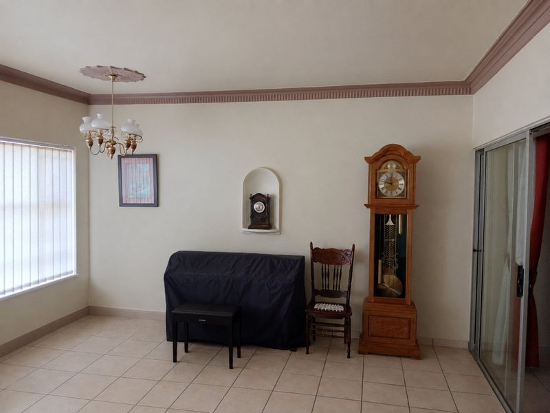 A living area featuring ceramic tile flooring, decorative ceiling rose, coved cornice, and a recessed wall niche, providing a neutral base for interior design.