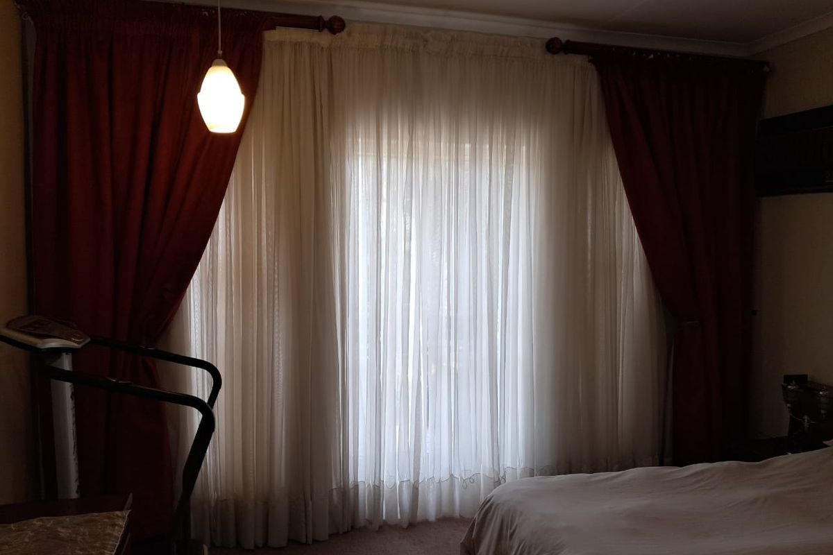 A bedroom featuring large floor-to-ceiling curtains and a pendant light fixture, providing a private and cozy atmosphere.