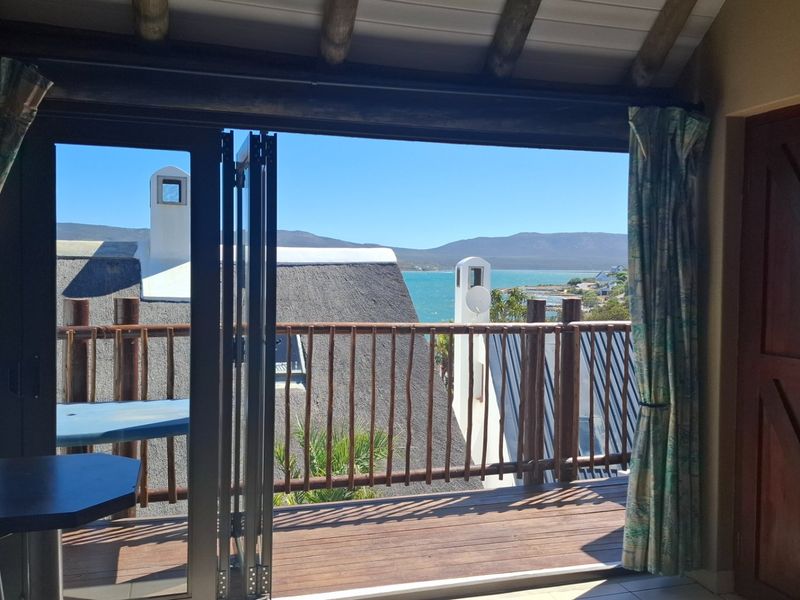 A covered balcony featuring timber decking and railing, offering scenic views of the surrounding landscape and water.