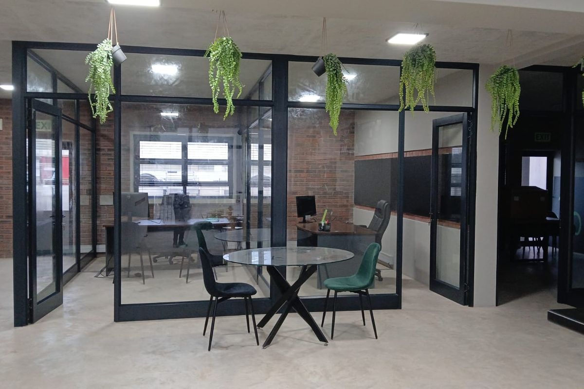Modern commercial office space featuring glass partition walls, exposed brick accents, and polished concrete flooring, creating a professional and contemporary work environment.