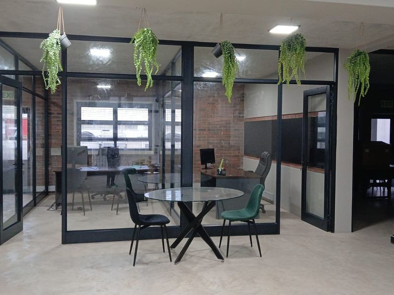 Modern commercial office space featuring glass partition walls, exposed brick accents, and polished concrete flooring, creating a professional and contemporary work environment.