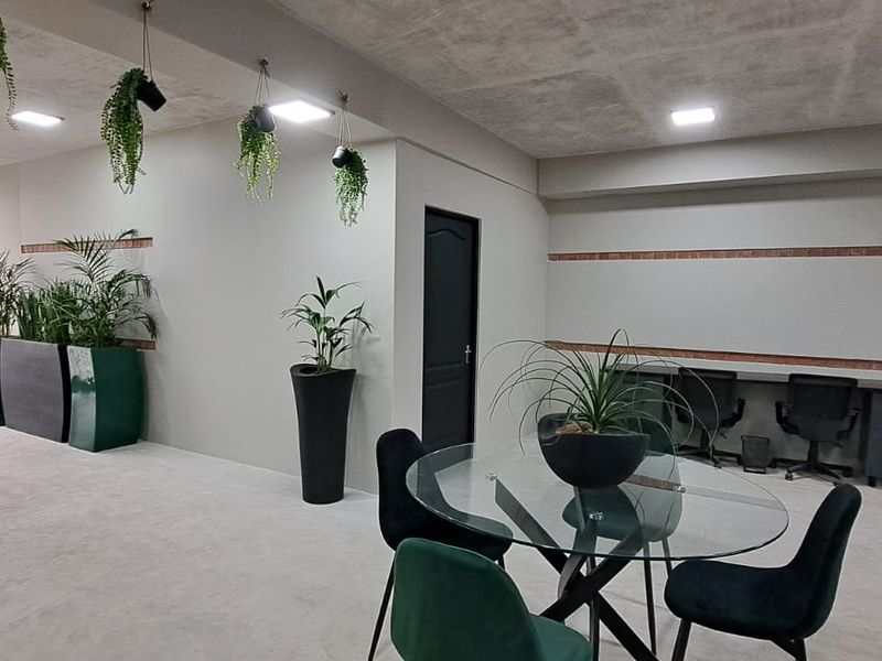 A modern commercial office space featuring a built-in desk, recessed lighting, and an exposed concrete ceiling, providing a professional and functional work environment.