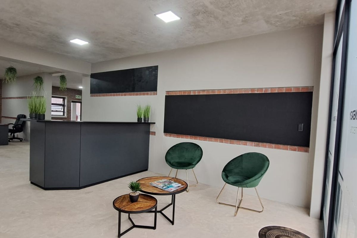 Modern commercial office space featuring a reception area, exposed brick accents, recessed lighting, and polished concrete flooring with an integrated glass entrance.