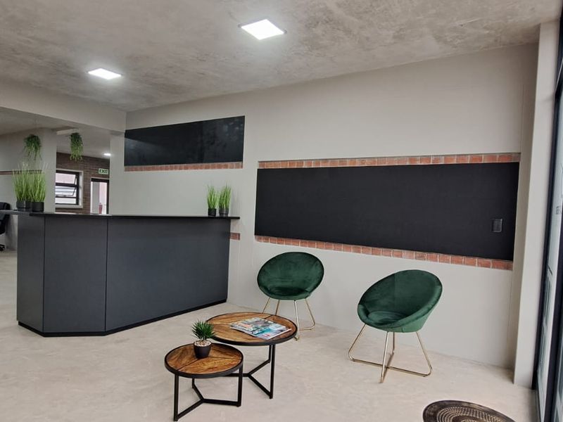 Modern commercial office space featuring a reception area, exposed brick accents, recessed lighting, and polished concrete flooring with an integrated glass entrance.
