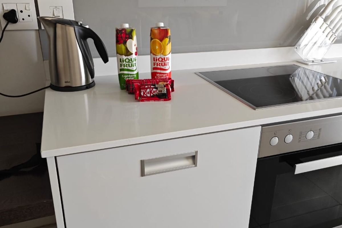 Modern kitchen featuring a sleek quartz countertop, glass splashback, induction hob, and high-end built-in oven with integrated extractor fan.