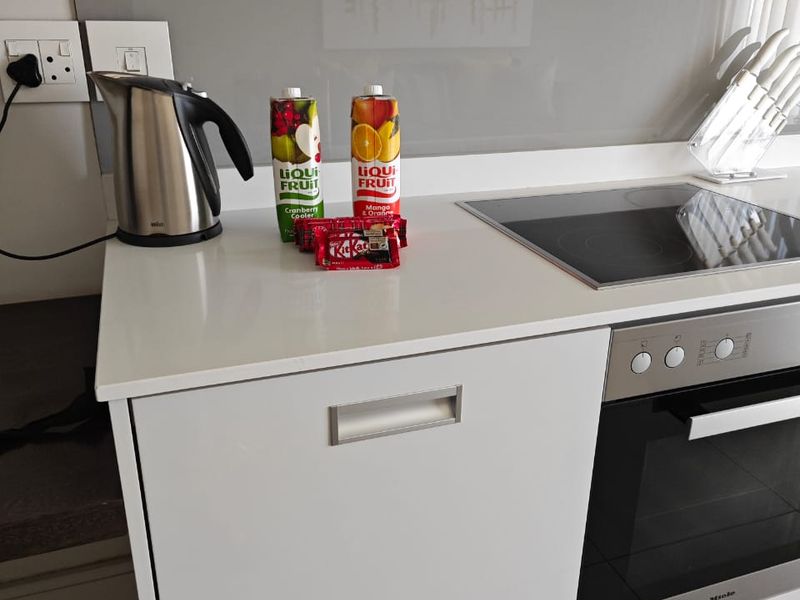 Modern kitchen featuring a sleek quartz countertop, glass splashback, induction hob, and high-end built-in oven with integrated extractor fan.