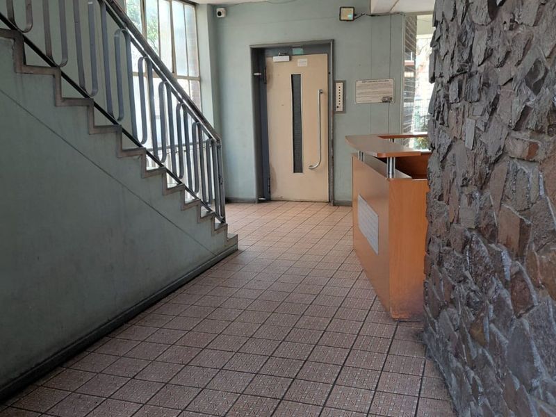 Building entrance lobby featuring a stone accent wall, tiled flooring, metal staircase, and elevator access.