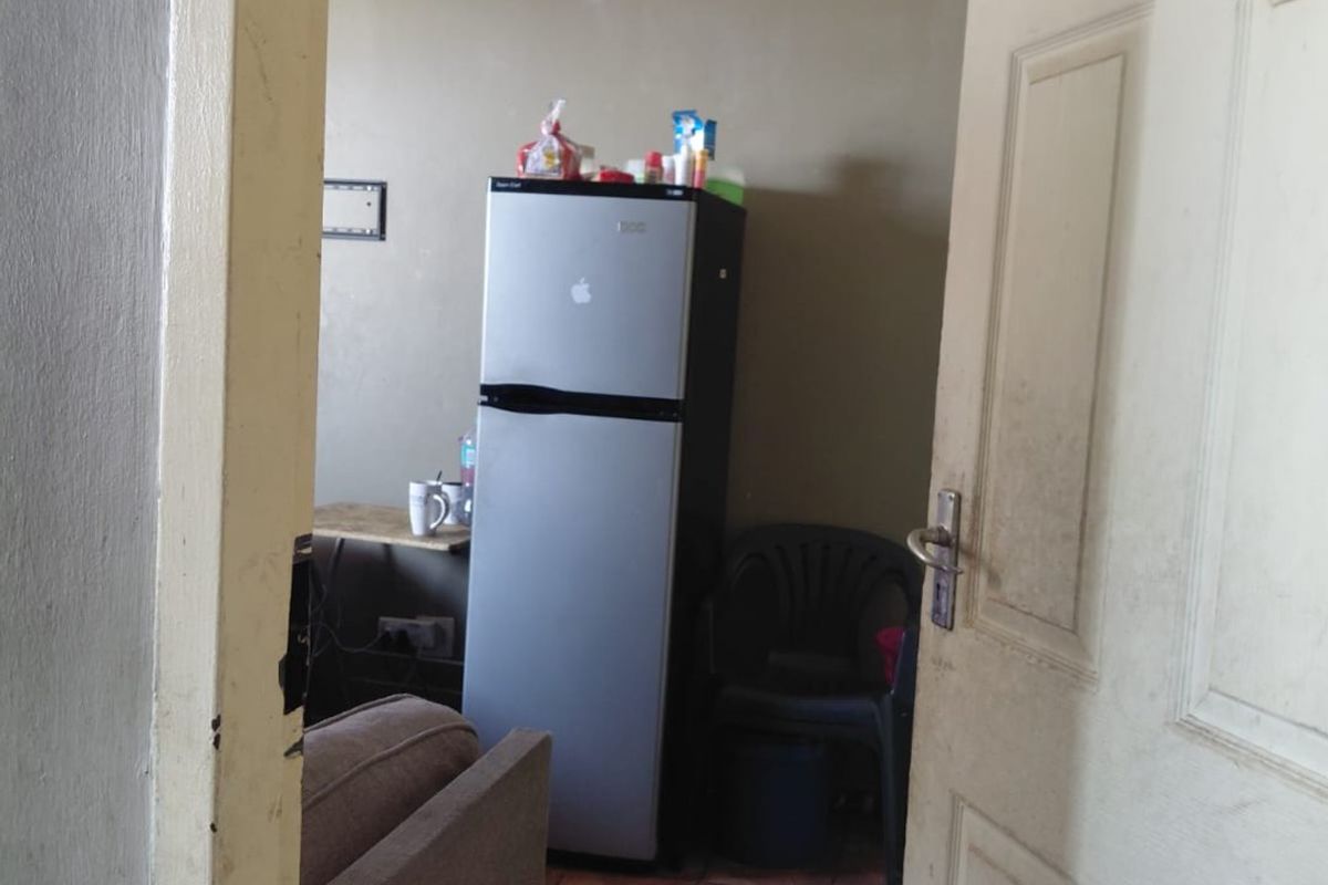 A view into a living area featuring tiled flooring and a standard panel door, showing signs of wear and requiring cosmetic updates.