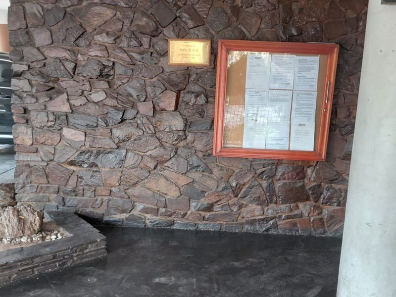 Entrance area featuring a stone-clad feature wall, concrete support column, and a wall-mounted notice board.