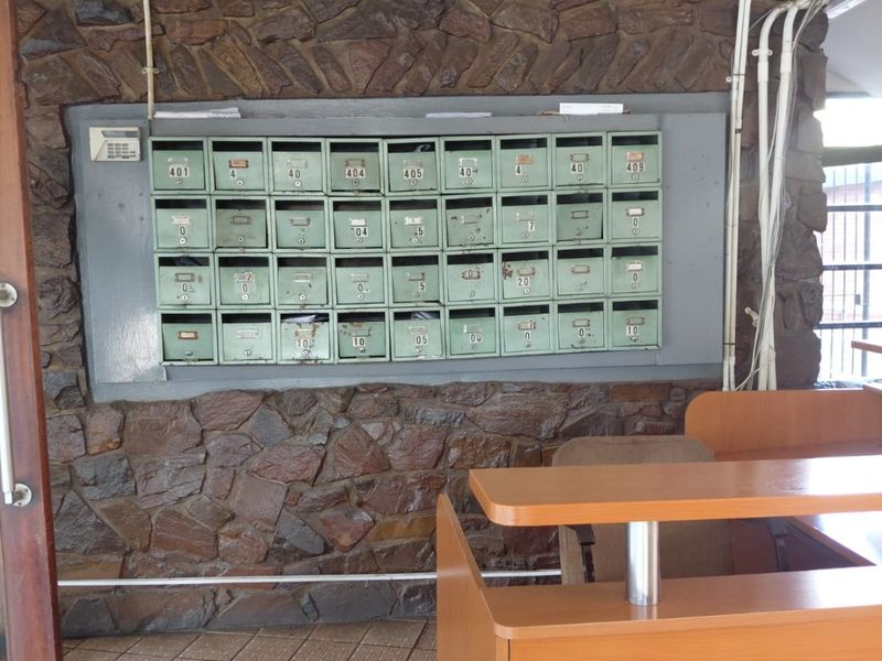 Apartment building entrance lobby featuring a wall of built-in mailboxes, stone cladding, and tiled flooring.