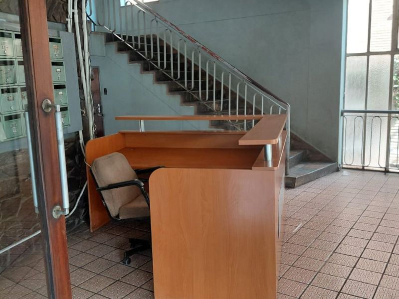 Apartment building entrance lobby featuring a staircase, tiled flooring, and a reception desk area with integrated mailboxes.