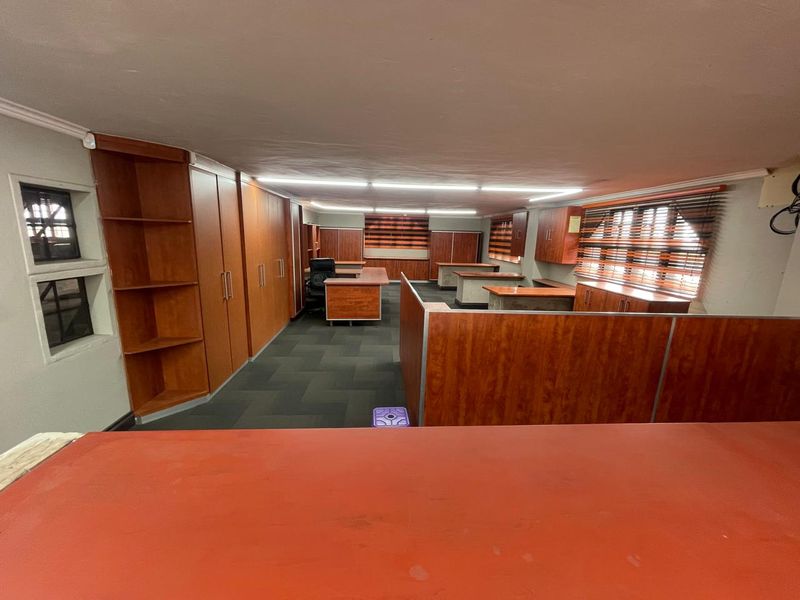 Spacious industrial office area featuring extensive built-in cabinetry, functional partitioning, and overhead fluorescent lighting.
