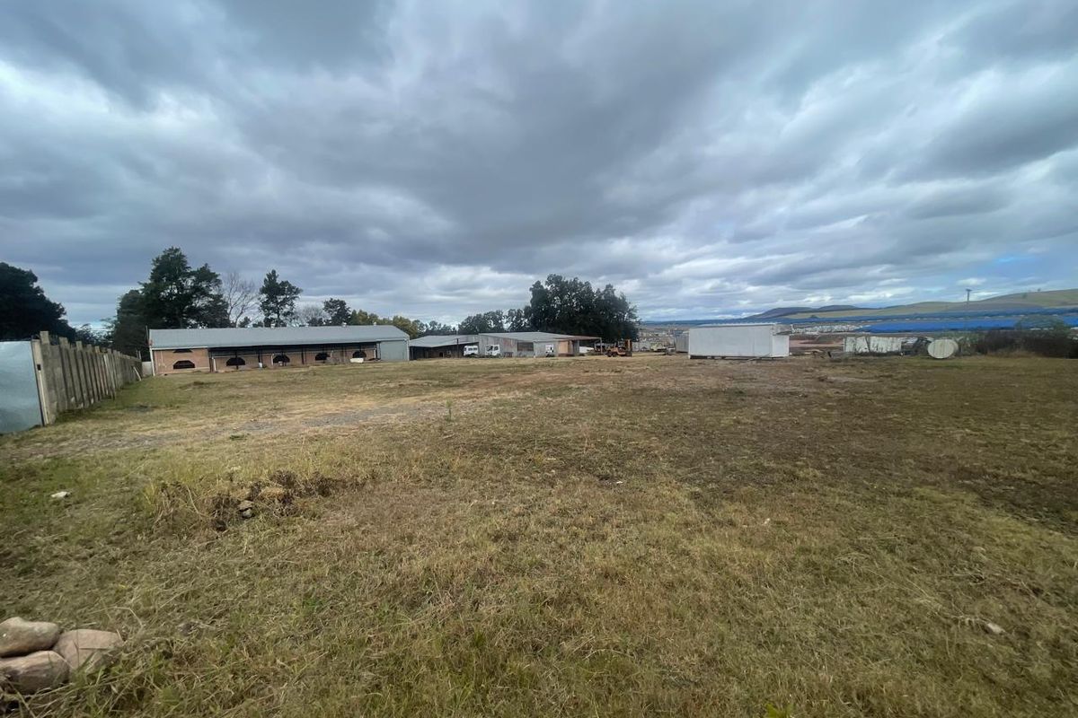 Expansive industrial plot featuring multiple storage sheds and open land, suitable for various commercial or industrial development opportunities.