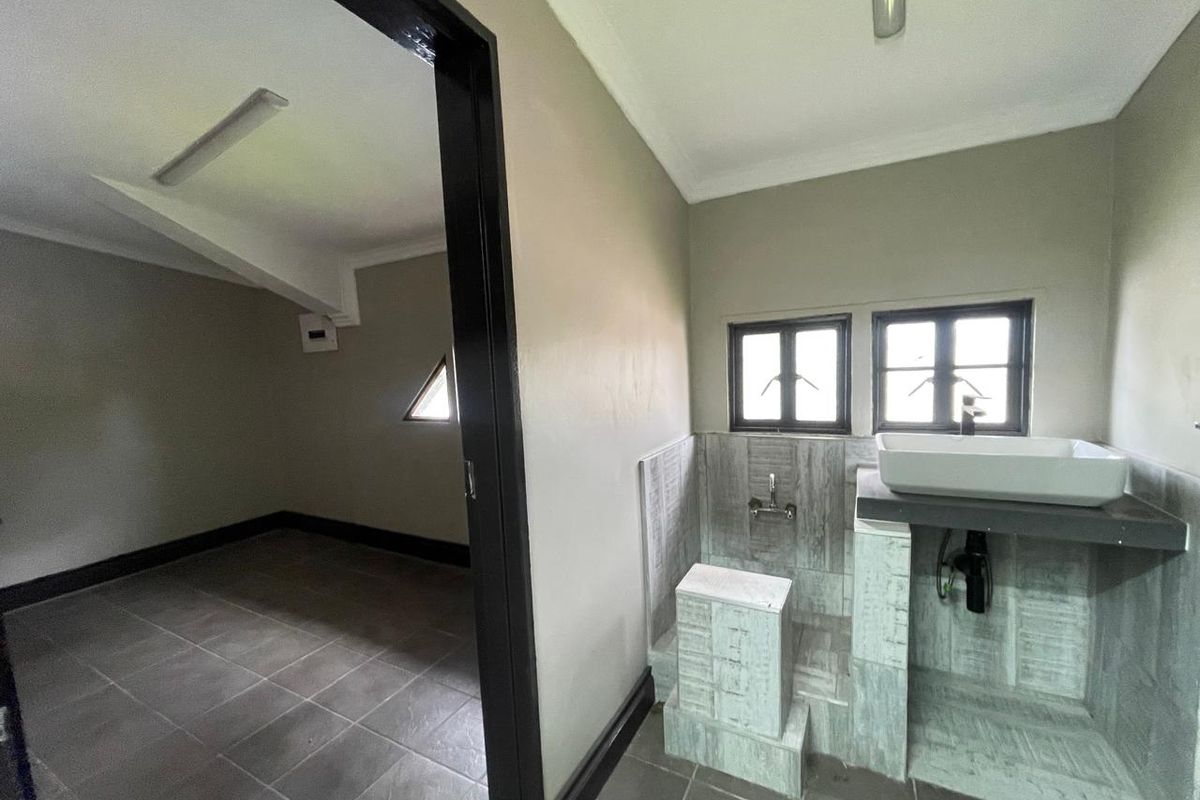 A functional bathroom area featuring a vessel sink on a tiled vanity base, adjacent to an empty room with tiled flooring.