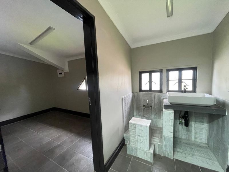 A functional bathroom area featuring a vessel sink on a tiled vanity base, adjacent to an empty room with tiled flooring.