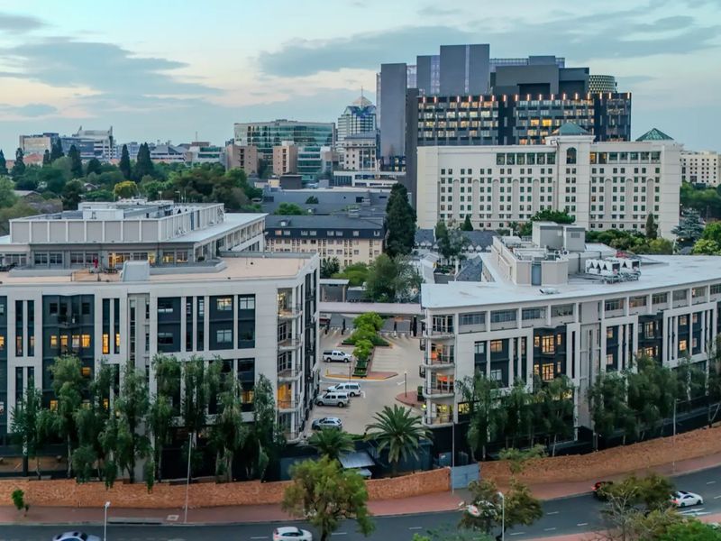 Aerial view of a modern commercial office complex featuring multiple buildings, paved parking facilities, and surrounding urban infrastructure.