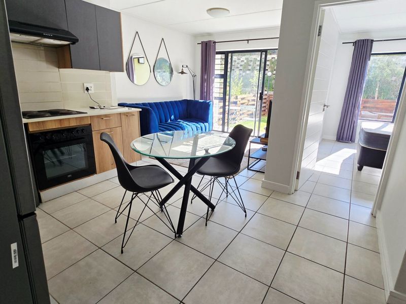 Open-plan living area featuring a modern kitchen with built-in oven and hob, tiled flooring, and direct access to an outdoor patio through sliding doors.