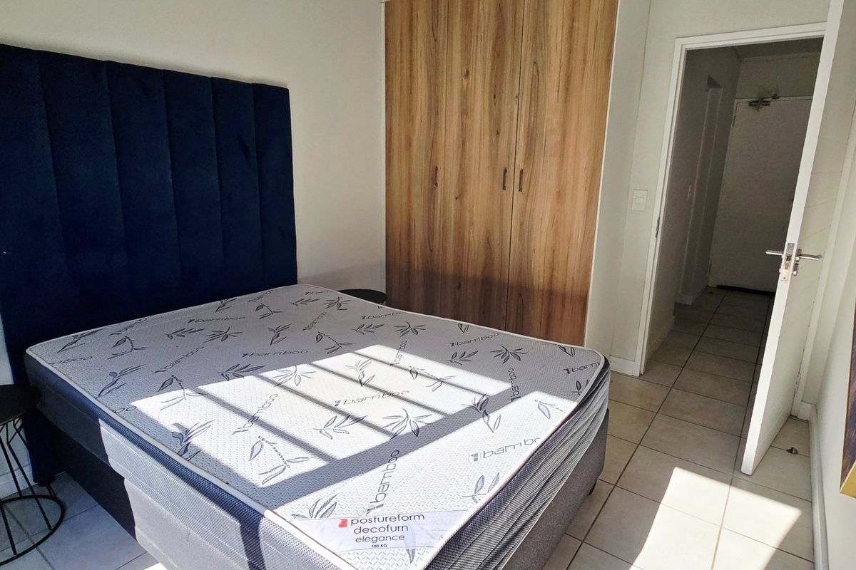 A bedroom featuring built-in wooden cupboards and tiled flooring, providing a clean and functional living space.