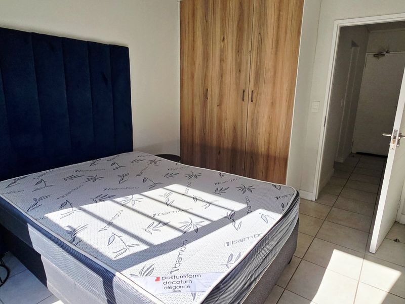 A bedroom featuring built-in wooden cupboards and tiled flooring, providing a clean and functional living space.