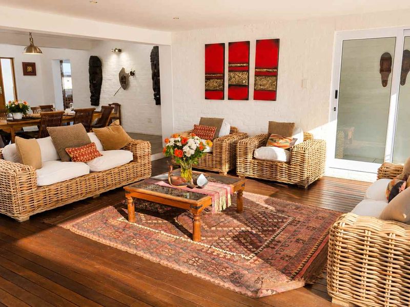 Spacious open-plan living area featuring warm timber decking, exposed brick walls, and large sliding glass doors providing seamless indoor-outdoor flow.