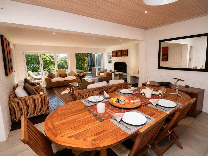 Spacious open-plan living and dining area featuring a timber ceiling, built-in fireplace, and seamless flow to the outdoor patio through bi-fold doors.