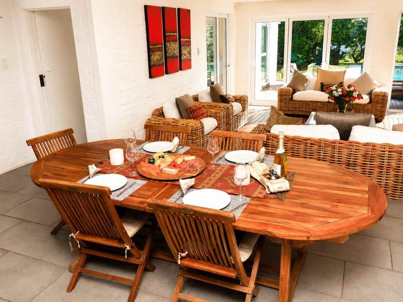 Spacious open-plan living and dining area featuring tiled flooring, painted brick walls, and large sliding glass doors opening to the outdoor pool area.