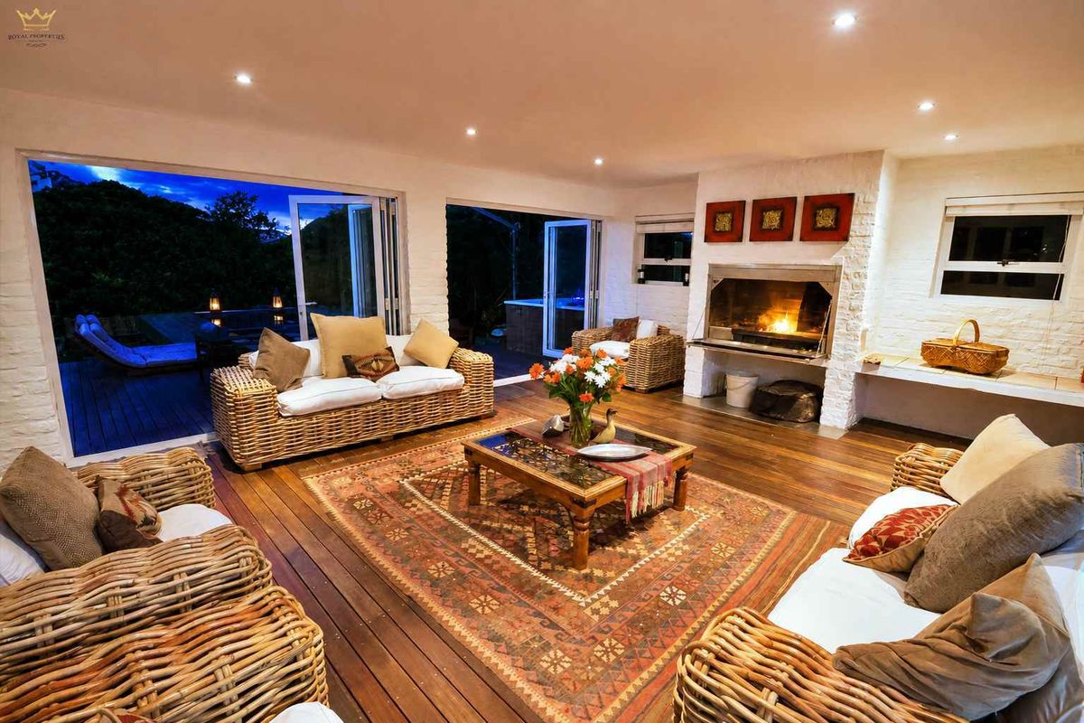 Spacious living room featuring timber flooring, a built-in fireplace, and large bi-fold doors opening to an outdoor deck area.