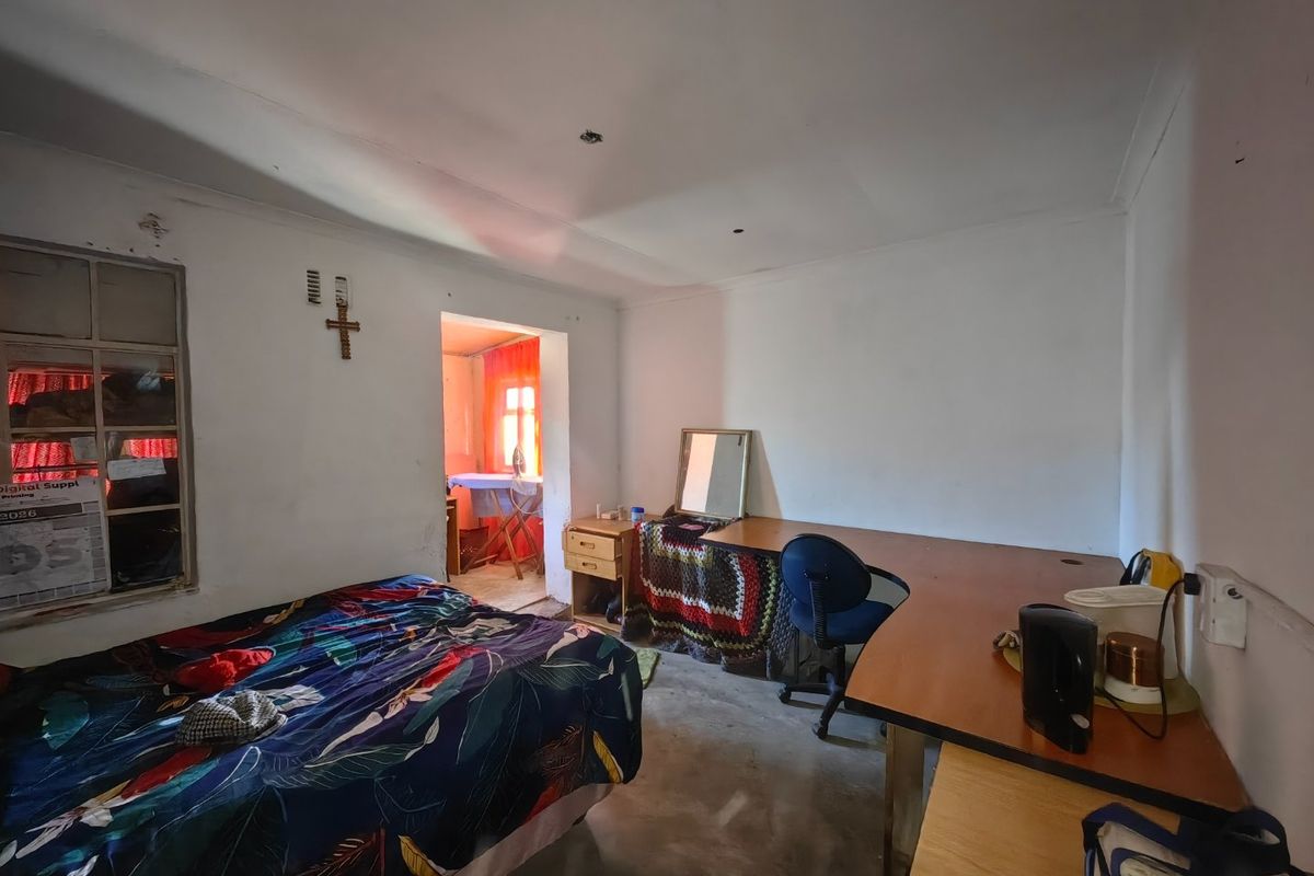 A bedroom featuring a metal window frame and basic electrical fixtures, currently showing signs of wear and requiring cosmetic updates.