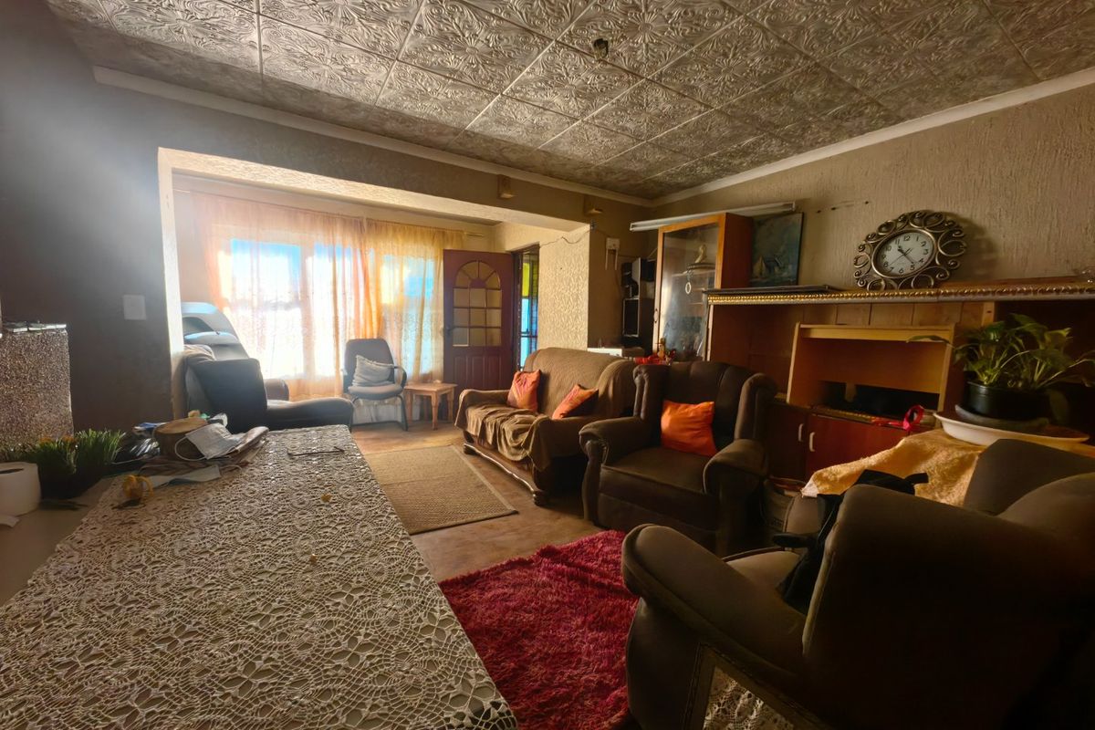 A living room featuring a decorative pressed metal ceiling and textured walls, offering a dated aesthetic with potential for modernization.